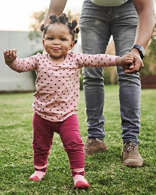 Father helping young daughter walk.