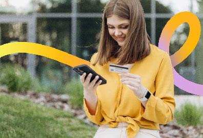 lady with debit card and phone smiling.