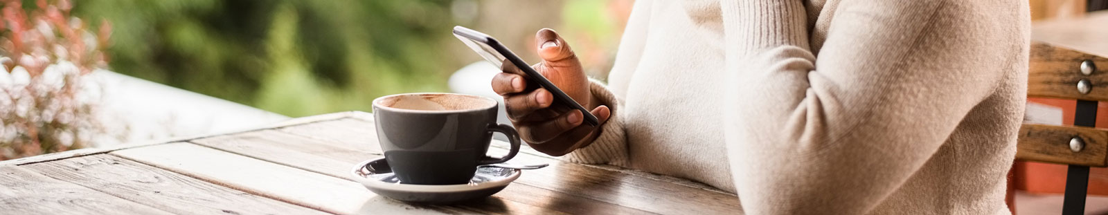 Woman holding phone with coffee.