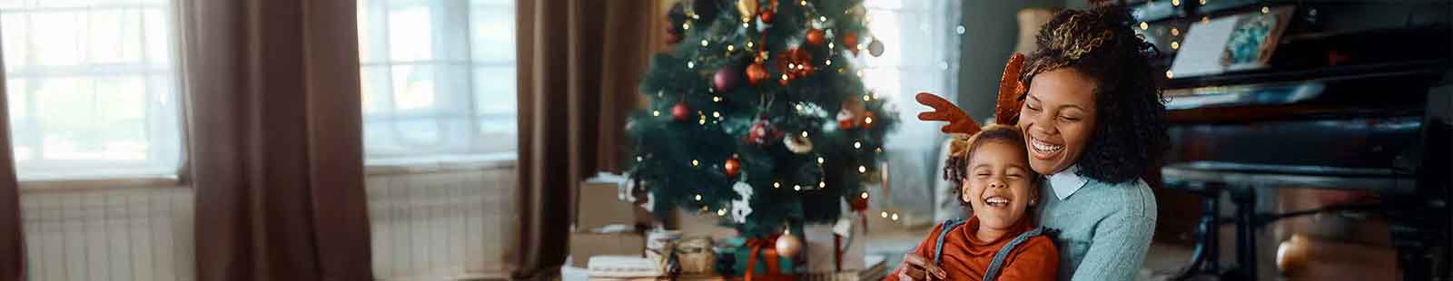 woman and child sitting by a Christmas tree hugging